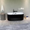 Modern bathroom with a glossy black freestanding tub, white interior, and a wall-mounted faucet against a gray textured wall.